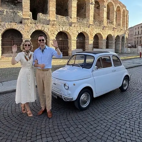 Una coppia in abito d'epoca saluta dall'auto davanti all'Arena, fotografia in bianco e nero